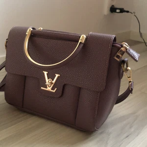 Mörklila väska  - Mörklila väska med guldiga detaljer. Gott med fack och fickor på insidan!💕