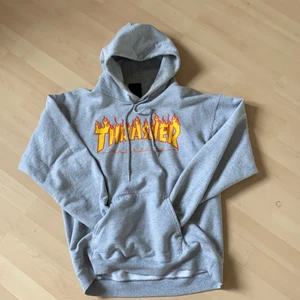 Thrasher Flame Hood strl S - Thrasher flame hood, använd men bra skick. Ena snöret på bilden är det enda som har liten slit skada men funkar bra ändå. Storlek S men rätt oversize, jag kan ha den men är mestadels mot M.