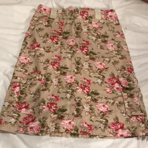 Blommig tygkjol  - Oanvänd kjol i kraftigt tyg. Likt jeansmaterial. Prislapp kvar. Fickor på sidor och bak.