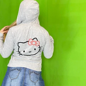 Hello Kitty Hoodie  - Hello Kitty Sanrio x H&M zip up hoodie från 2008. I ok skick för sin ålder. Storlek M. Modellen använder vanligtvis storlek S / M och är 169 för referens. Några få lösa stygn på hello Kitty loggorna. Inuti är hoodien urtvättad. Bustbredd 44/45cm, Axel till axel 40cm, ärmlängd 61cm och Hoodiens längd 57cm. Spårbar frakt på 66kr är inräknad i priset.  