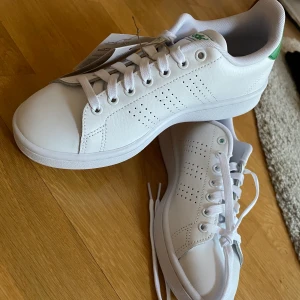 ADIDASSKOR  - Sprillans adidasskor, vita med gröna detaljer. Säljer pga fått dubbla. Storlek 38, prislapp kvar! Passar som träningsskor eller vanliga! 