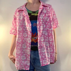 Rosa vintage Hawaii skjorta vita blommor - Rosa kortärmad vintage Hawaii skjorta med vita hibiskus blommor, krage och en ficka på vänster bröst 🌺  Denna skjortan är så snygg som en layering piece för en färgglad retro inspirerad outfit! Sätt på en färgglad baby tee med ett färgglatt tryck och ett par blåa jeans för en otrolig 90-tals outfit!