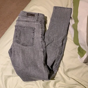 Gråa jeans, J Lindeberg - Som nya, nästan aldrig använda. Medium rise, slin fit, strl 25/34. Fin kvalitet. Säljes pga lite för långa på mig om jag inte viker upp dem (jag är ca 165 cm lång)