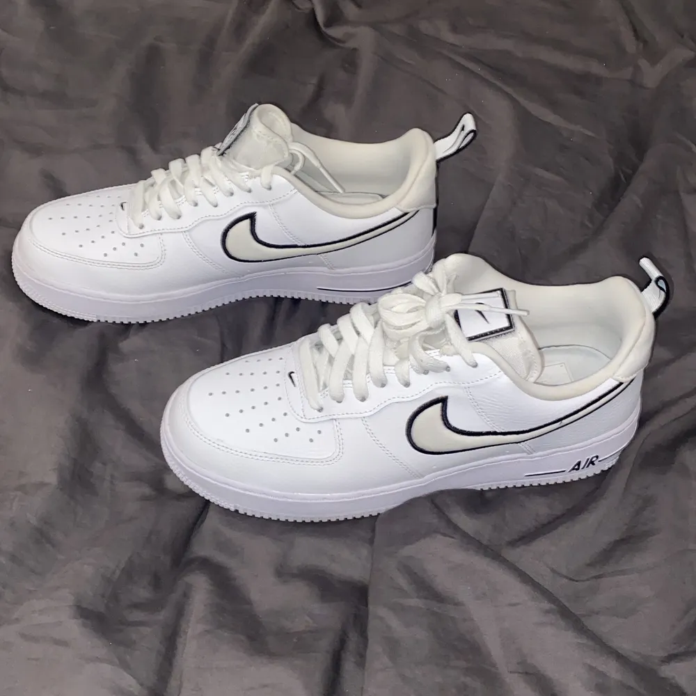 Vita Air Force 1 med svarta detaljer. Skor man kan ha på dig till de mesta, året om. Välvårdade skor som är lätt att ta hand om, med den roliga detaljen att de har Nike-loggan vid flärpen i kardborre så du kan plocka bort loggan och sätta dit valfritt.. Skor.