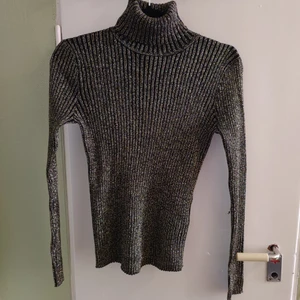 Guldig polo i ribbat stretchtyg från Monki - Aldrig använd, superfin polotröja i guldigt och svart ribbat tyg. 