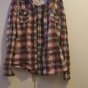 Peak Performance Skjorta - Orange och brun färgad skjorta med knappar från Peak Performance. Aldrig använd och i helt ny skick. Står ingen storlek på den men tror att den är en XL