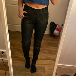 Svarta byxor  - Svarta byxor i skinnimitation med detaljer på knän och dragkedjor i byxbenen. Bra passform. Använda ett par gånger men i bra skick och håller stretchen i materialet 