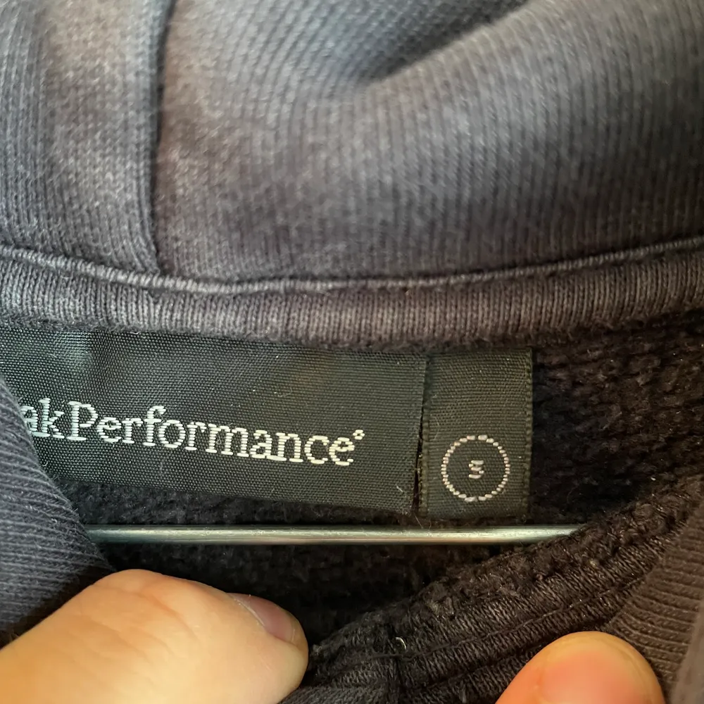 Mörkblå Peak performance hoodie i bra skick förutom att trycket börjar släppa lite därav priset. Storlek S. Vid köp av fler plagg fixar vi ett schysst paketpris!😊. Hoodies.