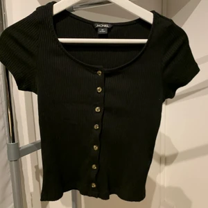 Croppad topp från monki  - Croppad och ribbad topp i svart med knappar. Har använts varsamt. Storlek XS men funkar även som S. 