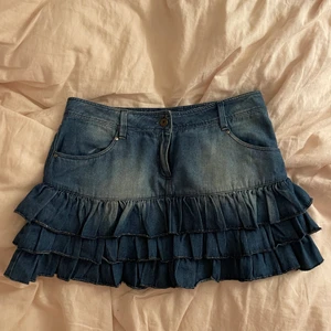 Jeanskjol med volanger - Supersöt jeanskjol med volanger som jag köpt second hand men tyvärr ej fått användning av. Storlek s, jag är 165 cm för referens. Kan mötas i Stockholm annars betalar köpare frakt. 