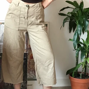 Beige oversized cropped byxor från UO - Beigea cropped byxor i bekvämt jeansmaterial från Urban Outfitters. Har ett litet hål vid dragkedjan annars i bra skick. 