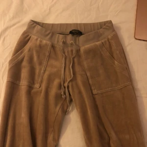 Juicy byxor - Supersnygga juicy byxor i mörk beige/ljus brun färg. I storlek XS, i super fint skick. Sitter bra i längden på mig som är 166 cm. En aning urtvättade, dock fortfarande lena. De enda defekterna är sista bilden på fickan, och en fläck på midjebandet där bak som man ser på andra bilden. Älskar dessa men får ingen användning av de. Skriv till mig för mer !