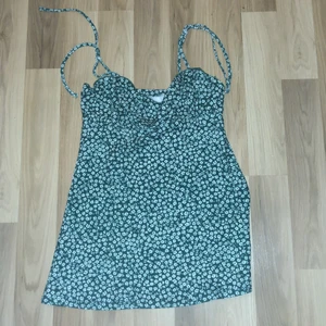 Fin blommig grön klänning - Storlek S. Blommig klänning med smala band vid axlarna 