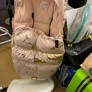 Bjällra of Sweden åkpåse  - Åkpåse från Bjällra of Sweden i ett exklusivt utförande med en pälskrage i fuskpäls som lätt kan knäppas av och på efter behov.  Vind och vattenavstötande yttre lager som håller regn och snö ute.  Hål för fempunktsbälte, kompatibelt med de flesta barnvagnsmodeller.  Resår vid toppen som går att vika runt ryggstödet samt överdel som kan plockas av helt.  Mått: Bredd, 49 cm, längd 100 cm.