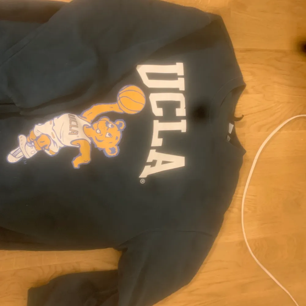 UCLA tröja, som ny förutom en defekt vid högra nedre hörn (se bild) . Hupparit & Collegepaidat.