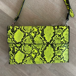 Neongul ormmönstrad väska från Zara - Söt liten neongul ormmönstrad kuvertväska med crossbody band från Zara. Har två fack och löstagbart band som går att förlängas/kortas, endast använd 2-3 gånger. Kan mötas upp i Stockholm City eller skickas på post, köparen står för frakten 🥰