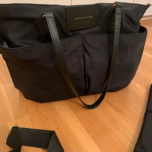 Skötväska Marc Jacobs  - Helt ny, super fin i skick! I märket Marc Jacobs köptes på Raglady för ca 2 år sedan.  Finns en lång extra axelrem och ett sköt underlägg som tillhör väskan.  Ordinarie pris är 3.500kr  Säljes för endast 1000kr 