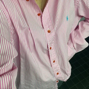 Ralph Lauren skjorta - Rosavitrandig Ralph Lauren skjorta i strl L, får en oversized passform på mig som är strl S. Använd en gång, säljer pga att färgen inte passar mig