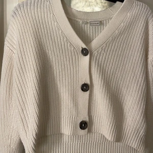 Kofta - En vit stickad kofta med knappar.