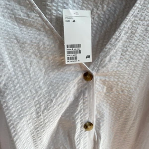 Blus  - Vit blus med knappar och knytning. Snygg till höga byxor eller som en blus att ta över bikinin på stranden. Prislapp kvar. 
