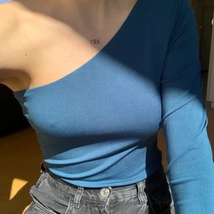 blå/grön one shoulder body - Den här fina bodyn är en perfekt fest-tröja, men går lika bra att användas till vardags!! Det är lite svårt att se färgen, men den är blå, med en hint av grön. Har inte använt den så mycket så den är i ett väldigt fint skick😍😍 Skriv om ni undrar något💘