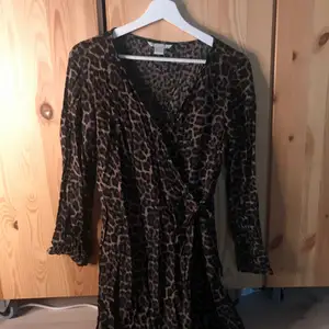 ALDRIG ANVÄND! Omlottklänning från H&M i storlek 36. Leopardmönster och knyte. Långa ärmar och själva klänningen går över knäna. En midiklänninh. Lågt pris pga möts ej upp utan skickar på post och köpare står för frakt! :)