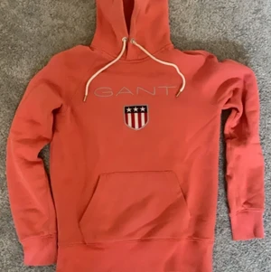 Gant hoodie storlek xs  - En mycket fin coral färgad gant hoodie med vita snören. Ganska tjock mysig hoodie från gant färgad som en solnedgång. Är i storleken xs är relativt använd men ändå i bra skick (9/10)