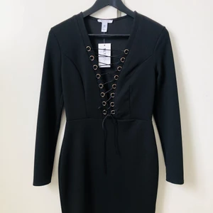 Svart klänning med snörning - Svart figurnära klänning från NLY ONE med snörningdetaljer fram. Oanvänd med prislappar kvar.