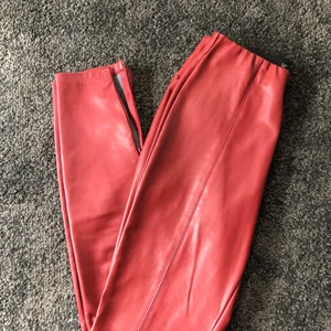 Röda skinnbyxor Zara Trafaluc  - fina röda skinnbyxor från Zara Trafaluc i strl S, sitter som en smäck och är i sparsamt skick. Dock är dragkedjan på ena byxans nedre ben sönder, men det påverkar inte skicket. Köpta för 400 kr men säljer för 200 kr! Köpare står för frakt.🧚🏼‍♀️🧚🏼‍♀️