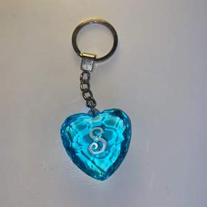 En blå diamant nyckelring som har formen av ett hjärta. Även med ett ”S” på vardera sida av diamanten. Den är några år gammal men i väldigt fint skick!