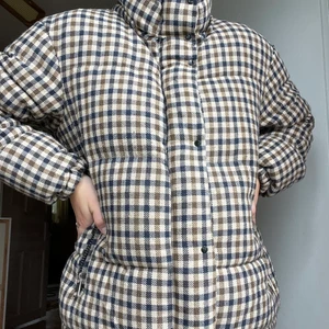 Rutig täckjacka - Säger hejdå till min svinsnygga täckjacka från Mango. Inköpt för ca 2 år sedan, men inte blivit använd särskilt mycket sedan dess. Därav i väldigt bra skick!   Storlek S, men väldigt rymlig och kan därför även passa en med storlek M. Den har en avtagbar huva och reglerbar ”midja”.  Köparen står för frakt. Men kan även kanske mötas upp i Stockholm 