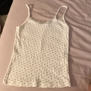 Linne med Spets - Säljer mitt gulliga Linne från Brandy Melville!🧡Den är vit med rosa blommor på och har även spets den uppe med en lite gullig vit ruset på!SKRIV TILL MIG FÖR FLER BILDER PÅ DEN!