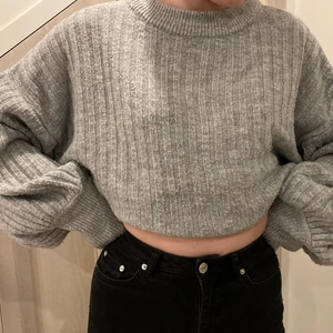 Grå stickad tröja - Grå ribbstickad tjocktröja. Färgen är ljus och lätt melerad. Plaggets storlek är L, modellen på bilden är storlek S. Varm och gosig, skönt material. Är i gott skick.