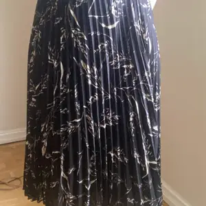Plisserad svart kjol med vitt mönster från H&M. Aldrig använt. Storlek: 34