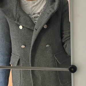 Höstjacka  - Grå kappa i kortare modell i strl XS men passar likaväl S, från ZARA. Silvriga knappar, fickor och en stor luva. Endast använd 2 gånger, så helt som ny. 