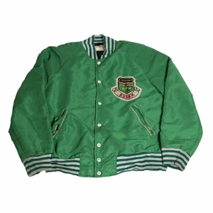 Essex - Vintage Baseball Jacka - En riktigt cool åttootalsjacka från England som öron en cool grön färg som är väldigt trendig just nu. Den är väldigt 80-talsaktig och gjord i nylon vilket är perfekt för ett lite kallare och blåsigt väder. Thriftad i England.