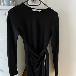 Svart klänning med knytdetalj - Säljer min jätte fina svarta klänning från NA-KD då den blivit för kort för mig (165 cm). Storlek XS. Knytdetalj i sidan att knyta själv, men sitter ihop med klänningen. Jätte fin passform, ganska tight i modellen för att forma sig efter kroppen. Köparen står för frakten 🖤