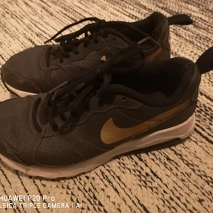 Nike Air sneakers -  Nike Air i svart och guld. Stl 37,5. Använda men i ok skick. Kan skicka fler bilder om intresse finns.  50 kr