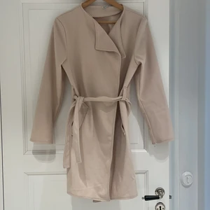 Beige kappa - Beige kappa med band att knyta i midjan. Från danska märket Creme Fraiche. Skulle tippa på att storleken är en S. Frakt ingår ej i priset. 