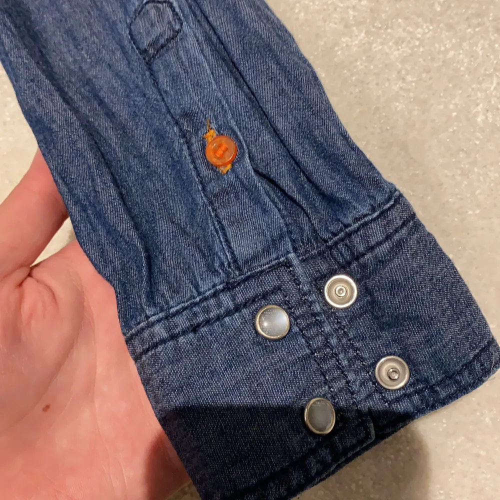 En denim blå randig skjorta med silvriga knappar. Använd ett par gånger. . Puserot.
