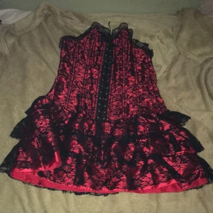 Korsettklänning m? - Köpt second hand, tror den är storlek m kan passa l tror jag. Cirka 66 cm lång och 82 cm i midjan som minst (går att töja ut). När jag köpte den så var det en knut som jag behövde klippa av på korsetten så man kan inte spänna ut den så mycket på en sidan.                                   Röd och svart med tyll.