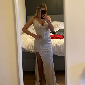 Klänning/balklänning  - Ännu än balklänning till salu. Silvrig, glittrig med slits. Storlek S men passar även XS, helt ny med prislapp kvar. 