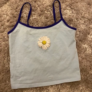 Blått linne - Jag säljer detta väldigt finna och snygga ljusblaå linnet. Det har mörkblåa stretchiga Axel band och själva materialet på linnet är också stretchigt så att det passar många olika storlekar. På framsidan är det en gul vit blomma. Den är i väldigt fint skick pga att jag bara använde den några få gånger. FRI FRAKT!!