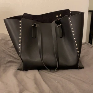 Svart handväska one size  - En svart stor öppen handväska med en mindre medföljande väska i (med dragkedja). Väskan rymmer mycket och är därav väldigt praktisk och med medföljande mindre väska kan man enkelt ha med sig t.ex. smink och andra hygienartiklar. Finns inget slitage, endast använd en gång. Gjord i fejk skin/läder. Anledning till att den säljes är för att jag inte använder den. Kostar 166 kr ink. frakt därav priset. 