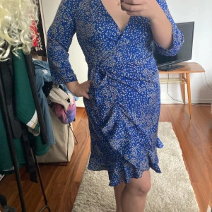 Klänning/Vero Moda  - Fin somrig oanvänd klänning i omlott. Mörkblå med vita blommor/blad detaljer. Köpt i Stockholm men är aldrig använd. Strl M och nypris är 350 kr, prislapp sitter kvar💕