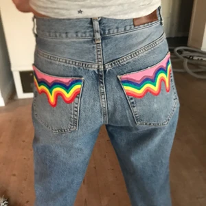 Rainbow drop jeans - Ett par Never denim jeans i storlek M som är köpta second hand!! Jag har målat en droppeffekt på de två bakfickorna i regnbågens färger 🌈. Jeansen är i bra skick och i en urtvättad blå färg. Jeansen har knapp gylf. Färgen är textilfärg som är fixerad vilket gör att man kan tvätta jeansen 😁💗