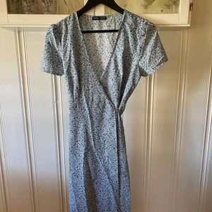 Ny blå omlottklänning - Ny blå omlott klänning! Endast tvättat men aldrig använd 💙 Det enda bandet har gått av lite då de fastande i tvätmakisnen men jag har knutit fast det, men man kan vara utan det med ☺️ Storlek M men passar även S