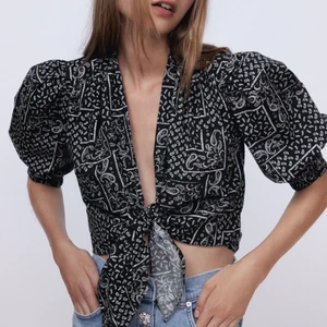 zara Blus med knut  - Helt ny och oanvänd blus med svart och vit mönster som man kan knyta framtill. Knuten kan man välja hur man gör med då det är sidorna på själva tröjan man knyter ihop. Söt blus som ger en timglasfigur pågrund av de puffiga ärmen. Passar både till fest och finmiddag.    