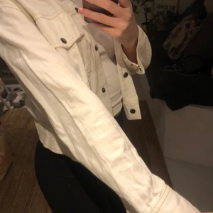 Vit jacka - En vit jacka i tunt jeansmaterial från ginatricot. Den har fina kontrastsömmar och knappar ifall man vill ha den stängd! Själva jackan är i en lite kortare modell och ärmarna är långa. 