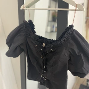 Svart topp - Off shoulder topp med ”puff” armar och knytning.